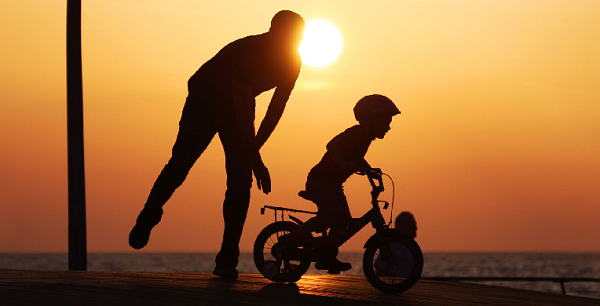 I believe in you. Child on bike with father.